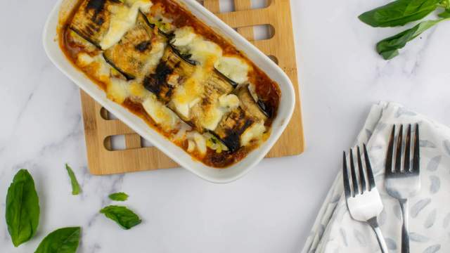 Eggplant rollatini with mozzarella cheese in a casserole dish with fresh basil.