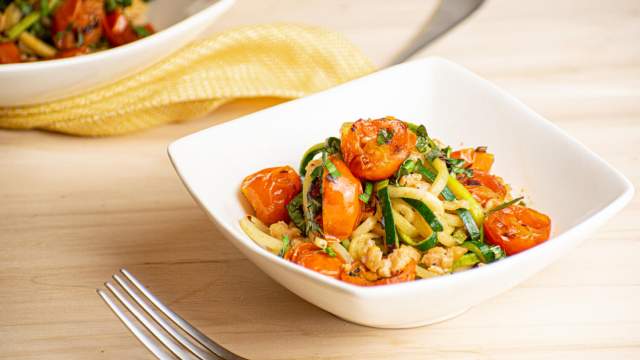 Garlic zucchini noodles with ground sausage and cherry tomatoes in a bowl.