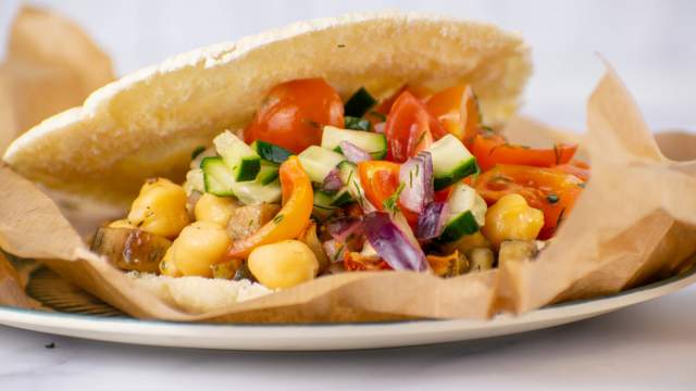 Greek tostadas with chickpeas, eggplant, tomatoes, red onions, and cucumbers on toasted pita bread.