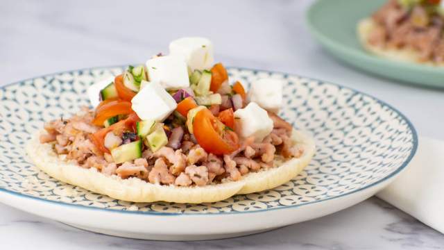 Greek turkey tostadas with tomatoes, cucumbers, and feta cheese on toasted pita bread.