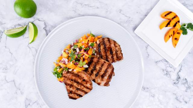 Grilled pork chops with peach salsa with fresh limes and peaches on the side.