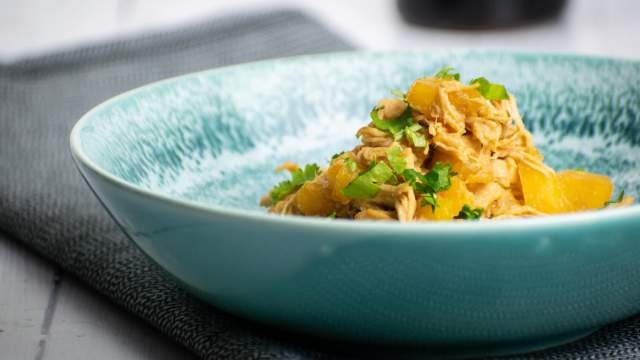 Slow cooker Hawaiian chicken with pineapple and cilantro in a blue bowl.