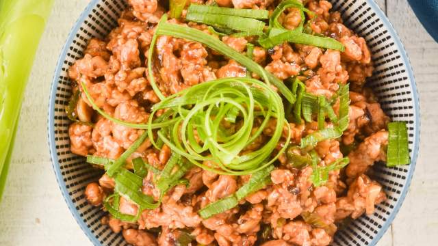 Healthy Mongolian chicken in a bowl with green onions on top.