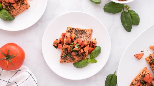 Italian salmon with a tomato basil salsa on a plate with fresh basil on the side.