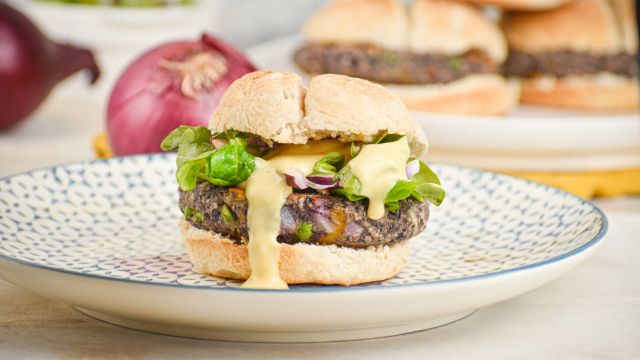 Jalapeno cheddar black bean burgers on a bun with lettuce, tomato, and onions.