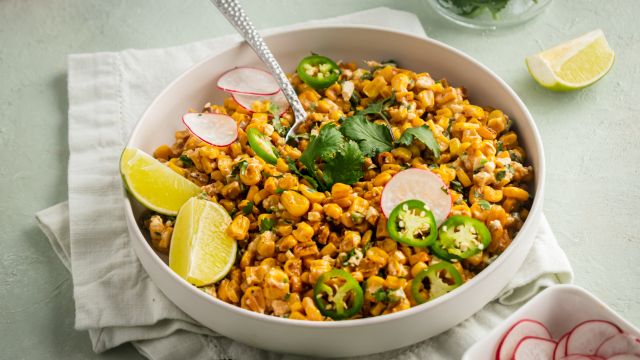 Healthy Mexican corn salad in a bowl with cilantro, corn, cheese, and jalapenos.