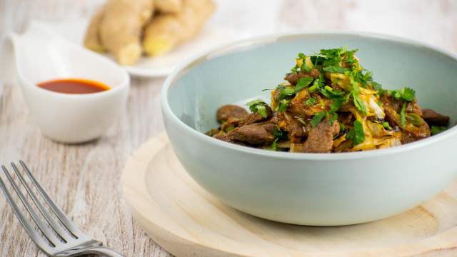 Moo Shu beef stirfry with sliced cabbage and cilantro in a blue bowl.