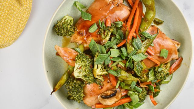 Teriyaki chicken and vegetables in a bowl with chicken thighs, carrots, broccoli, snap peas, and green onions.