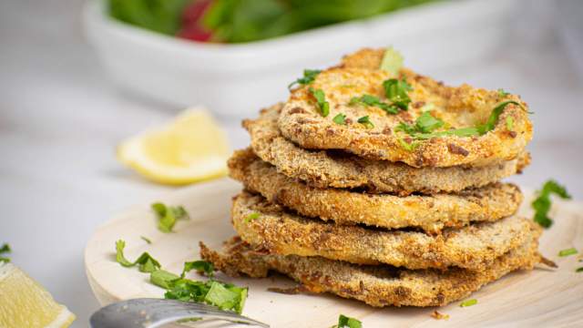 Parmesan crusted pork chops piled high with parsley and lemon slices.