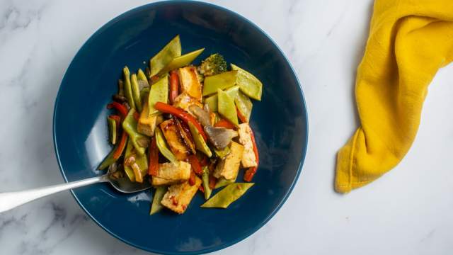 Sheet pan asian tofu with vegetables in a blue bowl with a yellow napkin.