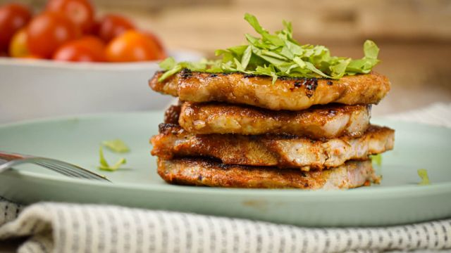 Sweet and spicy pork chops piled on a brown sugar spice rub on a plate with parsley.