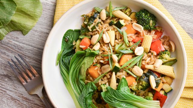 Teriyaki vegetable bowl with brown rice, bok choy, corn, edamame, carrots, and peanuts.