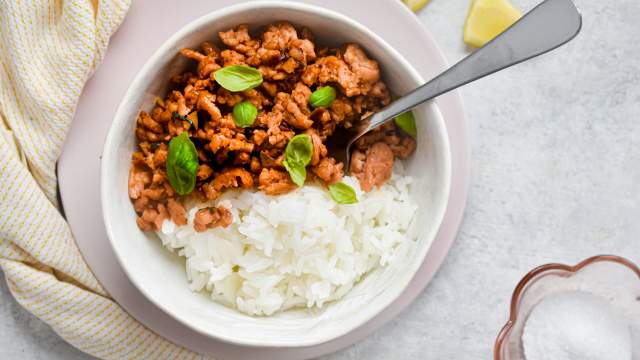 Thai basil ground turkey in a bowl with white rice and Thai basil leaves. 