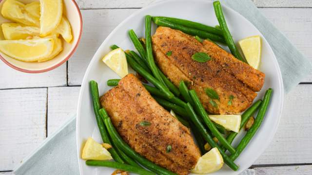 Tilapia with green beans, garlic, lemon, and a homemade spice rub on a plate. 