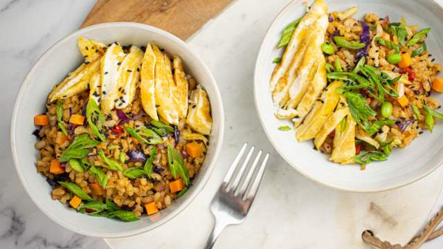 Vegetable fried rice with brown rice, eggs, carrots, peas, and cabbage in a cilantro.