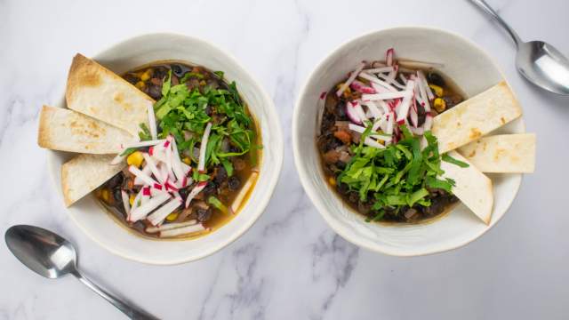 Vegetarian tortilla soup with radishes and cilantro on top with crispy tortilla strips.