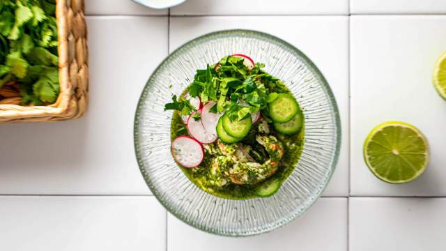 Aguachile with raw shrimp in a lime and cilantro sauce in a bowl with sliced cucumbers.