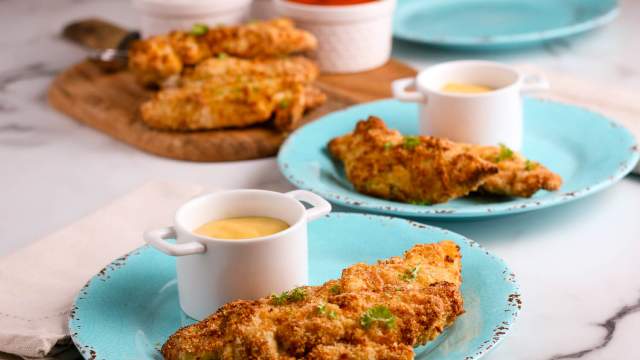 Air fryer chicken tenders with honey mustard sauce on two blue plates. 