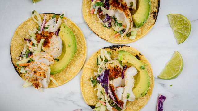 Fish tacos with lime coleslaw on corn tortillas with avocado.