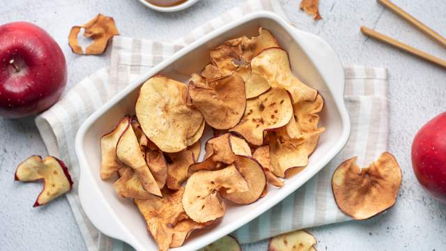 Apple chips with cinnamon that are baked until crispy in a ceramic dish.