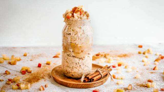 Apple cinnamon overnight oats in a glass jar with cooked apples and cinnamon on top.