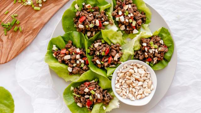 Asian ground beef lettuce wraps served on a plate with beef, mushrooms, peppers, and cashews wrapped in butter lettuce.