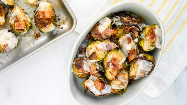 Bacon Brussel Sprouts with Parmesan cheese in a dish with a baking sheet.