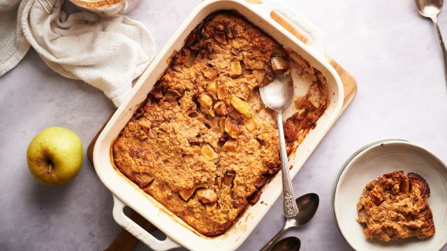 Baked apple cinnamon oatmeal in a baking dish with tender apples and a spoon.