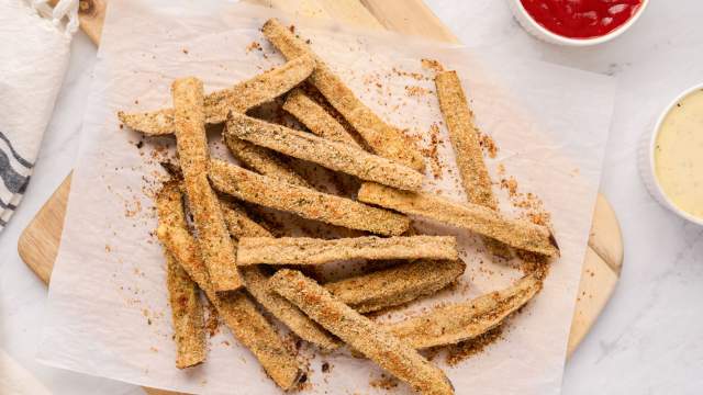 Baked eggplant fries with a crispy Parmesan and breadcrumb coating on a plate with ketchup.