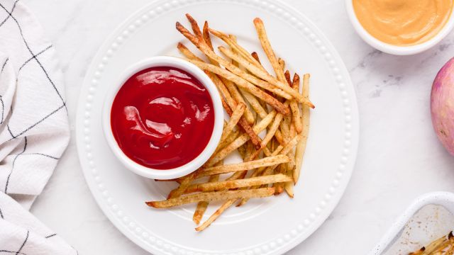 Baked skinny fries with crispy baked potatoes and turnips on a plate with ketchup.