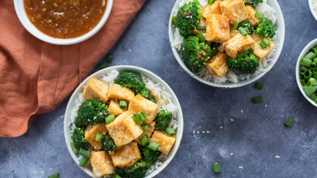 Baked tofu with sweet orange ginger sauce, broccoli, and rice in two bowls.