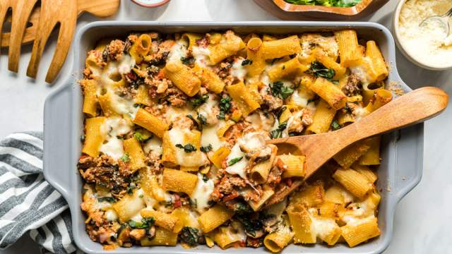 Baked ziti with ground beef, tomatoes, zucchini, and melted cheese in a baking dish.