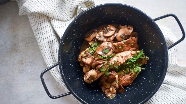 Balsamic chicken and mushrooms with fresh thyme and parsley in a bowl with a white napkin.