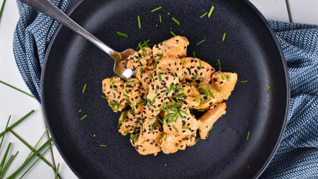 Bang Bang Chicken covered in a creamy sweet and spicy sauce with green onions and sesame seeds.