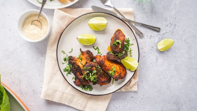 Blackened chicken breast with a crispy exterior on a plate with lime and cilantro.