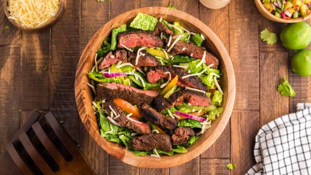 Blackened steak salad with thinly slcied steak over a bed of Romaine lettuce, red onion, peppers, and cheese.