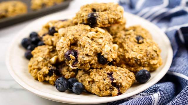 Blueberry breakfast cookies with rolled oats, bananas, fresh blueberries, chocolate chips, and chia seeds on a plate.