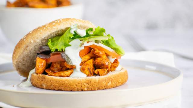 Buffalo chicken sandwich with blue cheese dressing on a bun with lettuce.