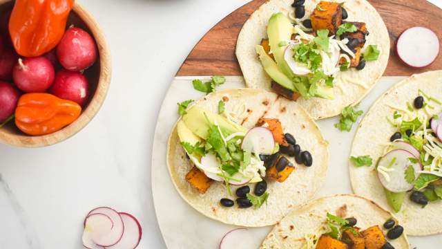 Butternut squash black bean tacos on corn tortillas with cilantro, cheese, avocado, and onions.