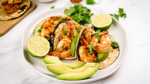 Cajun shrimp tacos in corn tortillas with sliced avocado, cilantro, and fresh lime juice.