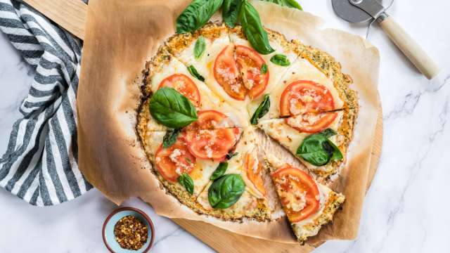 Cauliflower crust pizza made with cauliflower florets and topped with mozzarella cheese, tomatoes, and basil for a low carb pizza.