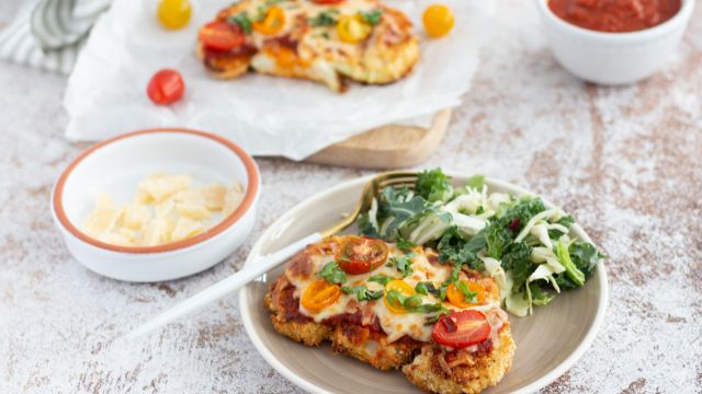 Cauliflower parmesan with breaded cauliflower steaks topped with marinara sauce, melted cheese, and cherry tomatoes.