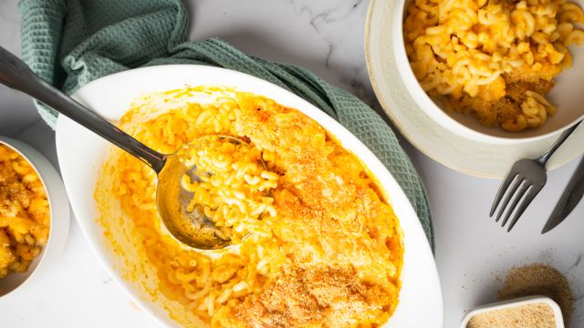 Cheddar carrot macaroni and cheese in a baking dish with crispy breadcrumbs on top.