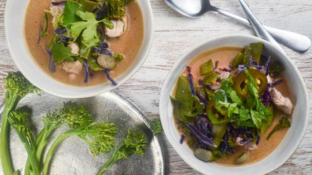 Chicken coconut curry soup with fresh vegetables, chicken breast, and red curry paste in a bowl.