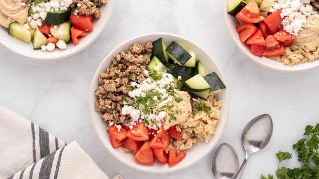 Chicken kofta bowls with tomatoes, cucumbers, hummus, and feta cheese in a bowl.