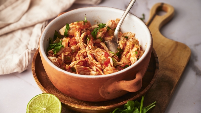 Chicken tinga in a bowl with onions, cilantro, avocado, and queso fresco.