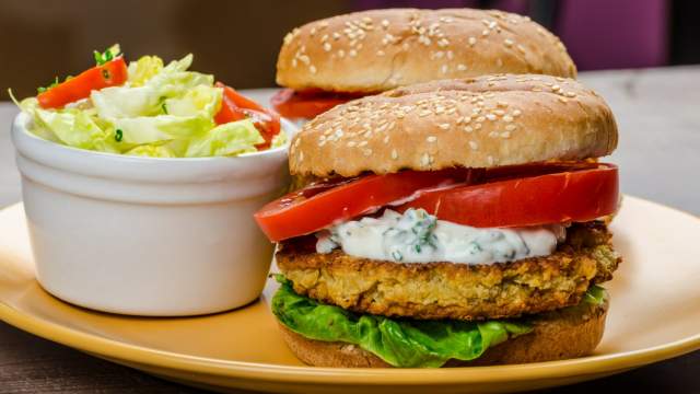 Chickpea burgers made with feta cheese topped with yogurt sauce, lettuce, and tomatoes.