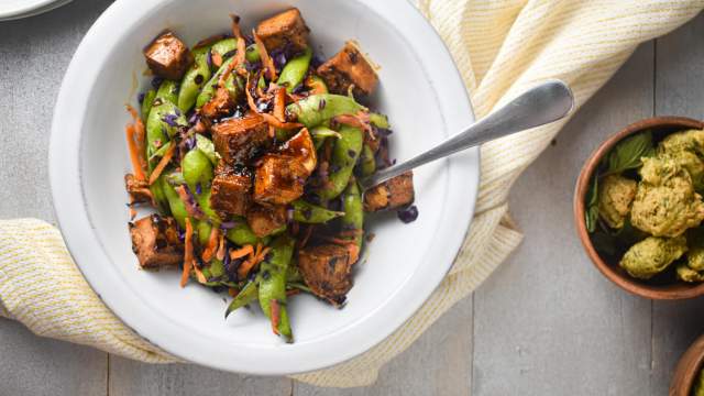 Chili Glazed Tofu with cabbage, snap peas, carrots, and tofu in a bowl with a napkin.