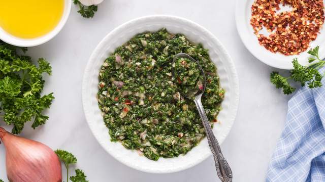 Chimichurri sauce with parsley, garlic, olive oil, red wine vinegar, and shallots mixed together in a small bowl.