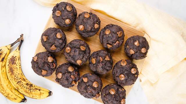 Chocolate banana muffins made with ripe bananas on a wooden board with chocolate chips.